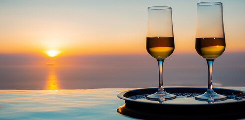Romantic relaxing atmospheric  summer sunset over the sea from the infinity pool with two wine glasses. Beauty of nature lifestyle background 