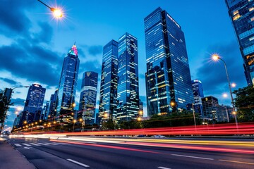 Fototapeta premium Cityscape featuring towering illuminated skyscrapers, light trails from traffic on a bustling street, and a vibrant blue sky, symbolizing urban energy. Ai generative