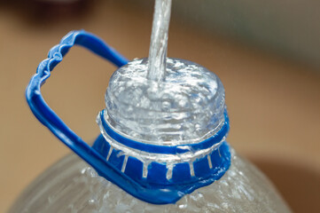 a jet of water fills a plastic container. a stream of water flows into a plastic bottle with a...