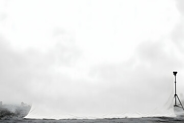 Minimalist monochrome photography featuring a large white backdrop, camera on tripod, and hazy cityscape in the distance; ideal for design, advertising, or editorial projects.