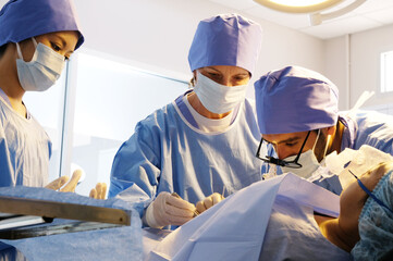 Male doctor and medical assistant performing surgery on patient in operating room.