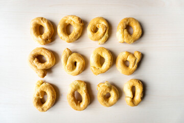 Flat lay of artisanal homemade typical apulian taralli, used as a baked snack in south italian culture. The taralli are placed on a clean and clear background