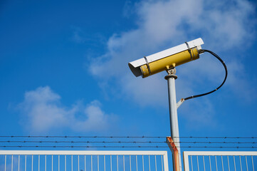CCTV Surveillance camera on a fence with barbed wire