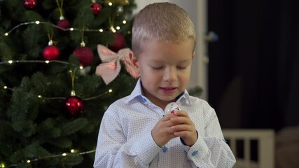 Happy child holding snow globe with figurine of Santa Claus. Smiling face of little boy near Christmas tree. Merry Christmas and Happy New year winter holidays.