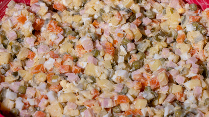 A bowl of food with a variety of ingredients including carrots, peas, and ham