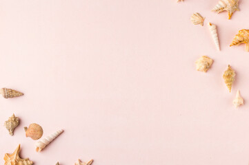 Spiral shells and charms on pastel pink and green background. Pastel flat lay featuring spiral shells and charms.
