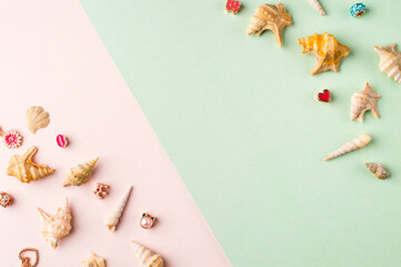 Seashells and jewelry on pastel pink and green background. Pastel flat lay featuring seashells and colorful jewelry.