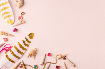 Seashells and jewelry on pastel pink and green background. Pastel flat lay featuring seashells and colorful jewelry.