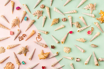 Seashells and jewelry on pastel pink and green background. Pastel flat lay featuring seashells and colorful jewelry.