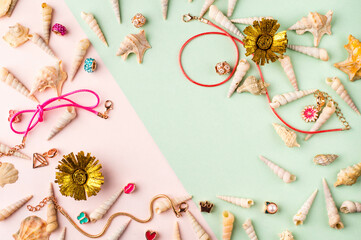 Seashells and jewelry on pastel pink and green background. Pastel flat lay featuring seashells and colorful jewelry.