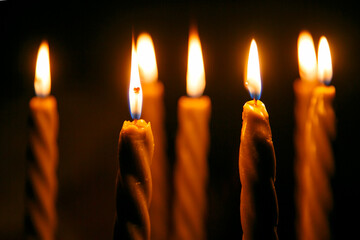 Burning candles on dark surface against black background