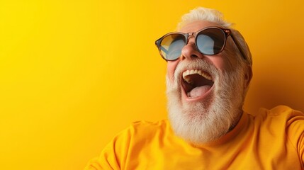 An elderly man in a yellow shirt and sunglasses joyfully laughs, his open mouth expressing happiness against a solid bright yellow backdrop.