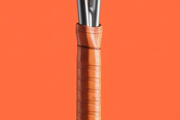 Fototapeta premium Close-up of an orange tennis racket grip, showcasing textured design and metallic shaft.