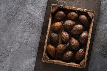 Fototapeta premium Top view of an old brown avocado in a wooden box. The concept of aging, storage and spoilage of fruits, as well as a beautiful textured background.