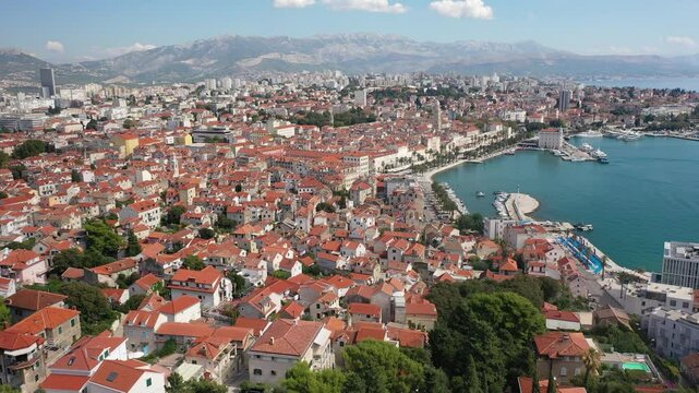 Captivating drone footage of Marjan's first viewpoint, capturing the vibrant city of Split drenched in sunlight. A picturesque blend of blue seas, historic landmarks, and the green Marjan forest.