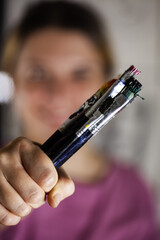 Artistic girl holding many dirty colorful used brushes.