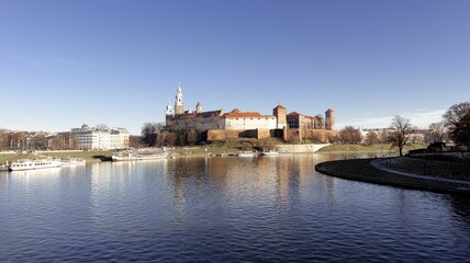 Fototapeta premium The Wawel Castle and the Vistula River under a clear blue sky in Krakow, Poland.
