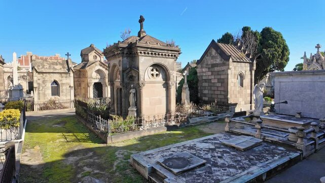 Row of mausoleums, known as panteones, standing in a sunlit Spanish cemetery.