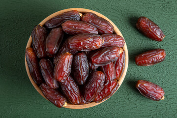 Large dates fruit in a wooden bowl on green background