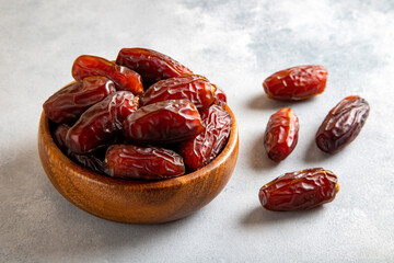 Large dates fruit in a wooden bowl on bright background