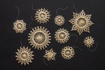 Snowflakes are made of straw on a black background. Christmas decor. Top view. Straw weaving. Lutsk, Ukraine