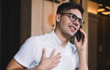 Positive male talking on smartphone in cafe