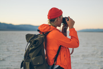 Female hiker taking photo in dry desert in USA