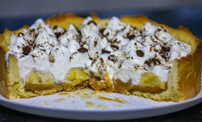 Traditional banoffee cake with banana and caramel sauce filling sprinkled with grated dark chocolate and coffee . English traditional pie