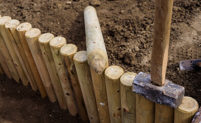 Construction of a small wooden fence in the garden behind the house to create a step in sloping...