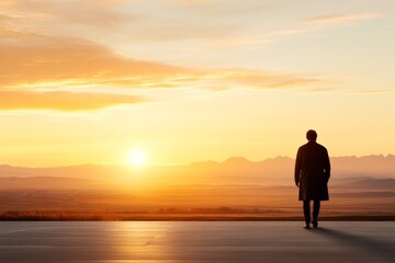 Fototapeta premium Man standing alone at sunset overlooking mountains and valleys in serene landscape