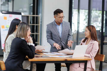 Business Asian people, laptop and conversation with research, teamwork and connection in the office. Group, employees and accounting with computer, internet and cooperation with meeting and planning