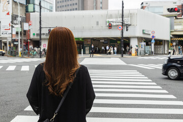A woman waiting at the pedestrian pathway to cross a street in Tokyo, Japan, on her way to the...