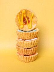 One mini pies with colorful topping decoration. small tart cakes and pies isolated on yellow background. Small cupcakes with colorful chocolate decoration
