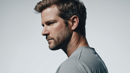 Obraz premium Profile of a man with a thoughtful expression in a minimalist studio setting during a photoshoot