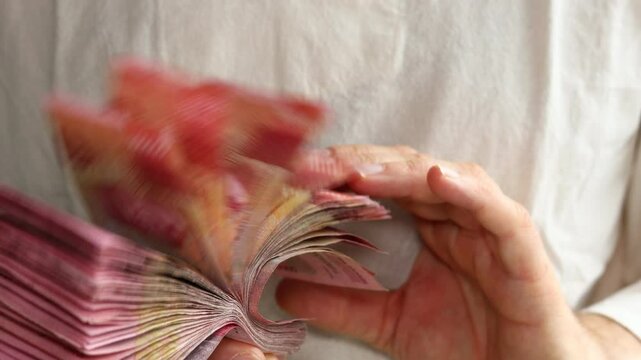 Indonesia a lot of money. Indonesian rupiah in the hands of a man. The highest denominations, a stack of one hundred thousand rupiah banknotes. Financial business concept.