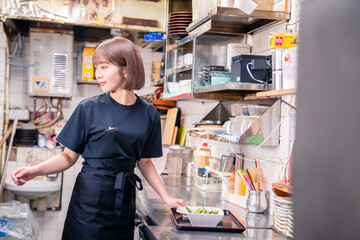 居酒屋の厨房で働くキッチンスタッフの女性