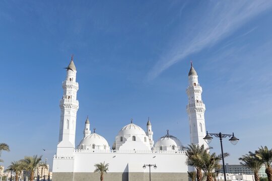 Madinah, Saudi Arabia - December 19, 2024: View of Quba mosque with date palm trees and clear blue sky