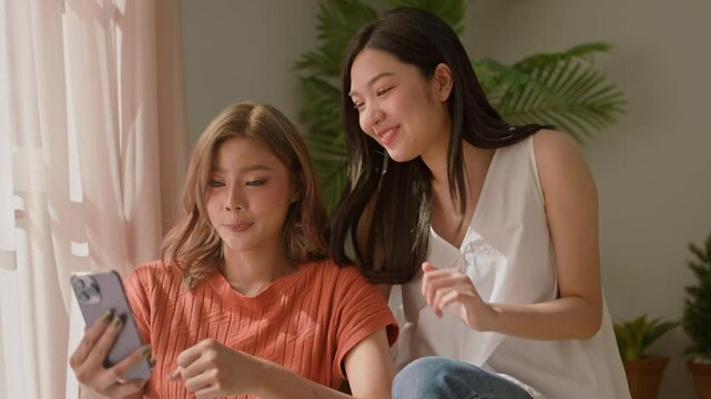 LGBT Lesbian asian couple love moments happiness concept.two lesbian girls sits on stairs of new apartment and video call with family.Enjoy asian lgbt couple woman selfie together