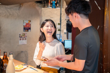 Fototapeta premium 焼き鳥屋さんの女性客と店員