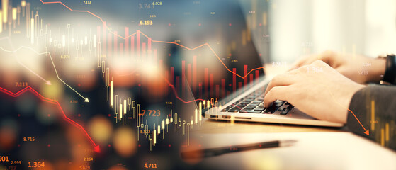 Financial data charts overlaying hands typing on a laptop on a blurry office background representing stock market analysis and trading.