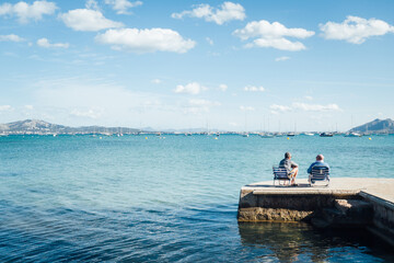 Deux hommes assis au bord de la mer méditerranée. Deux vacanciers aux Baléares. Touristes à...