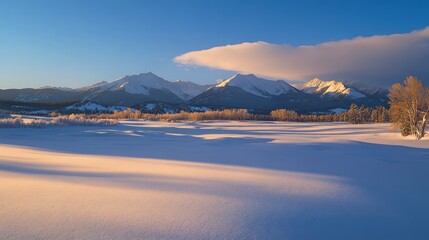 Snow-covered landscape with mountains under a clear blue sky.
