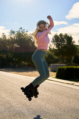 Young sporty woman jumping with inline skates and listening music with headphones in a park