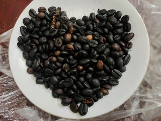 Roasted coffee beans with heart shape on a white plate