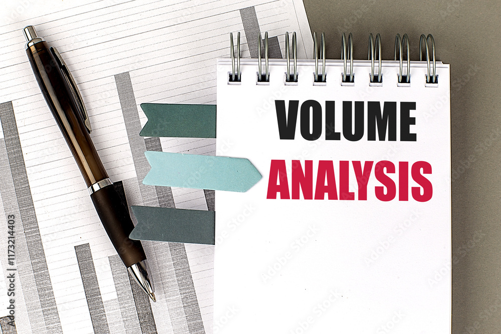 Poster volume analysis text on a spiral notebook with bar charts, colored tabs, and a pen on a desk