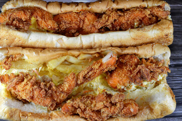 Spicy crispy chicken pieces, French potato fries, lettuce, coleslaw, mayonnaise and cheddar cheese in a sesame long bun, a western chicken long sandwich with fried chicken and burger sauce