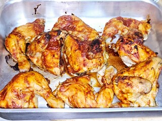 Baked chicken quarters in the oven, chicken pieces with bones baked and covered with tomato paste in a tray, selective focus