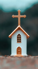 Miniature church model with cross, symbolizing faith and spirituality in a serene setting.