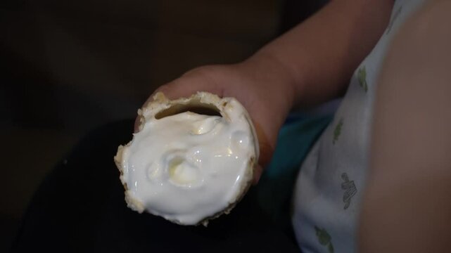 A young Asian boy, full of curiosity, gently touches the ice cream with his fingers, savoring the moment as he licks it with delight. It's a sweet reminder of the simple joys in life.