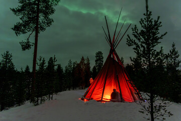Sami tent with Northern Lights in Lapland Inari Nellin Lake forest